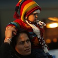 A migrant carries a baby on her shoulders after refugees and migrants arrived on the passenger ferry Blue Star1 at the port of Piraeus, near Athens, Greece, January 31, 2016. Photo: Darrin Zammit Lupi