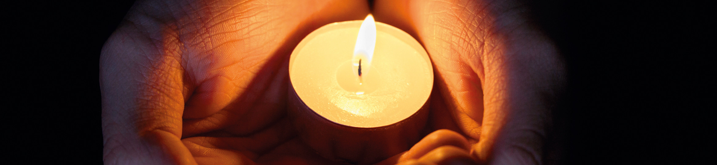 female teen hands holding burning candle in the dark