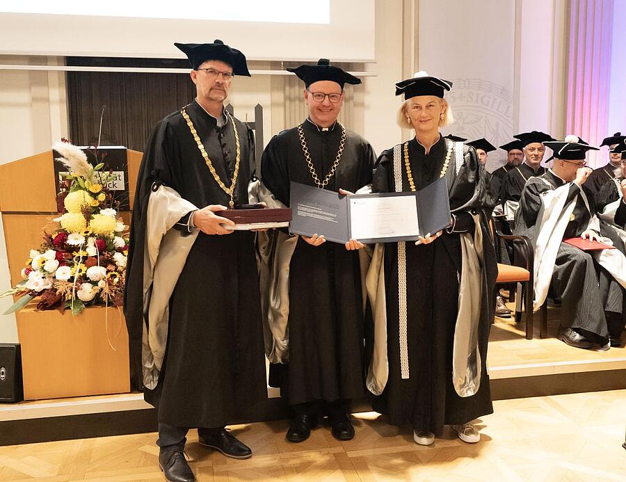 P. Christian Marte bekam am 18. Oktober 2024 die Ehrensenatorenwürde der Universität Innsbruck verliehen. Dekan Wilhelm Guggenberger (li.), und Rektorin Veronika Sexl (re.) gratulierten ihm dazu.