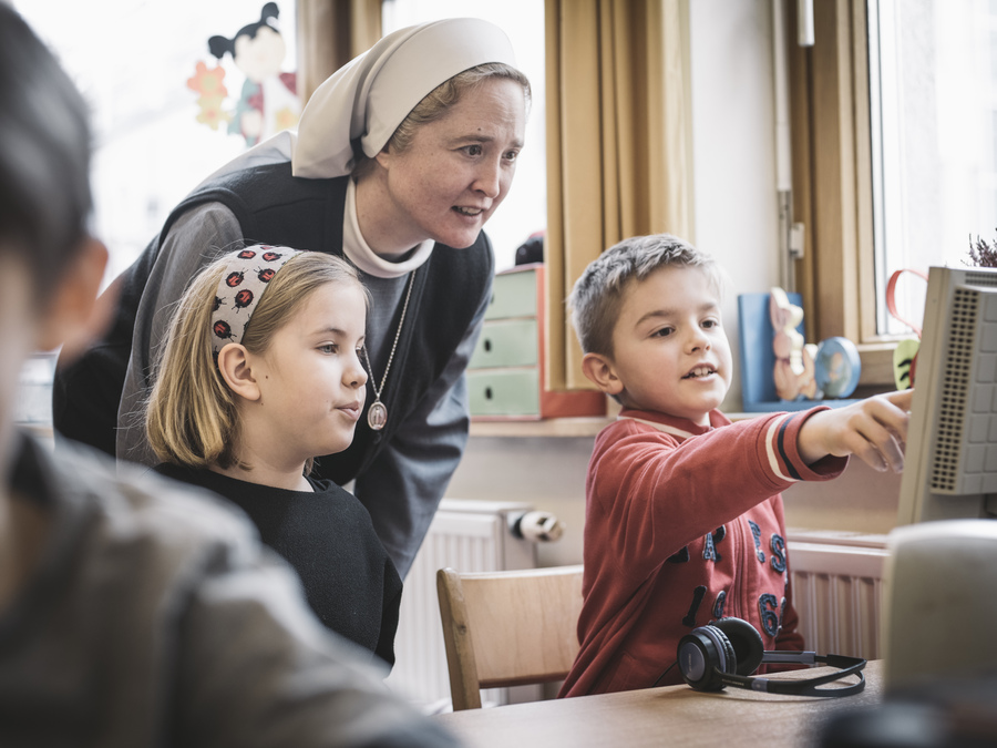 Das Bild zeigt eine Ordensfrau mit Schüler:innen