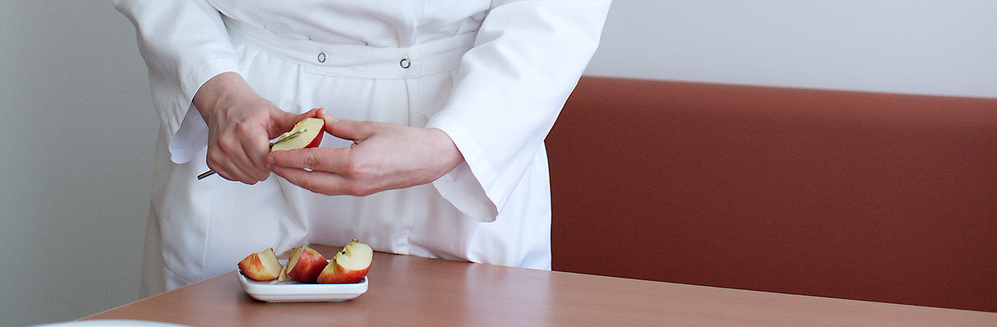 Das Bild zeigt Hände die gerade einen Apfel aufschneiden