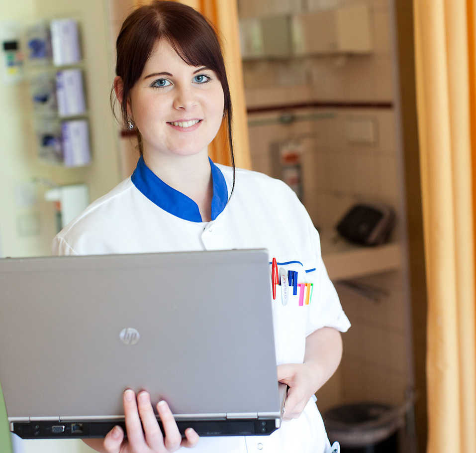 Das Bild zeigt eine Mitarbeiterin eines Ordensspitals mit einem Laptop in der Hand. 