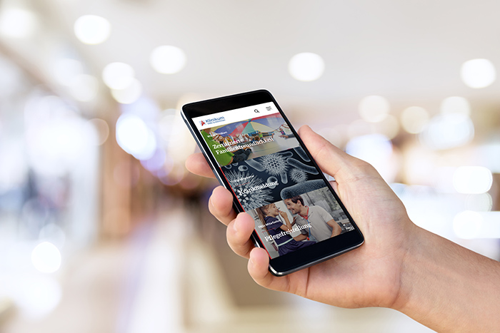 Hand holding mobile smart phone with blank screen / Preto_perola Man`s hand holding mobile smart phone with blank screen at blurred shopping mall background.